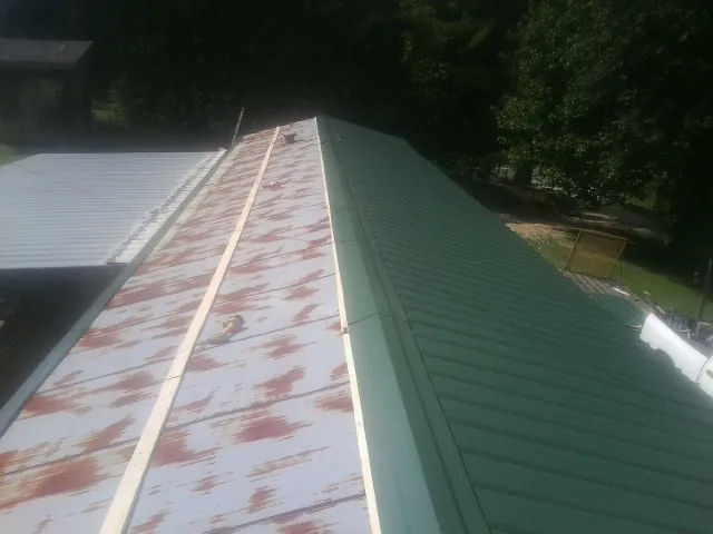 Old rusted panels beside newly installed green metal roofing — Wind Damage Roof Repair by Roofing Brothers in Anadarko