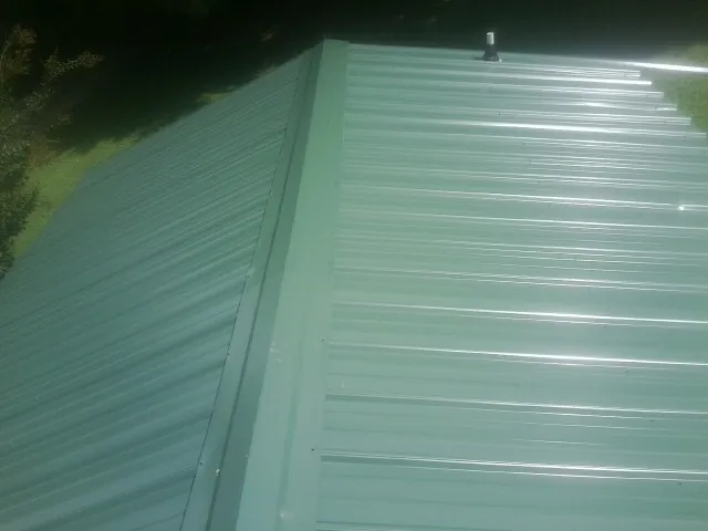 New green metal panels meeting at the ridge of a roof — Flat Roof Repair work by our crew in Anadarko
