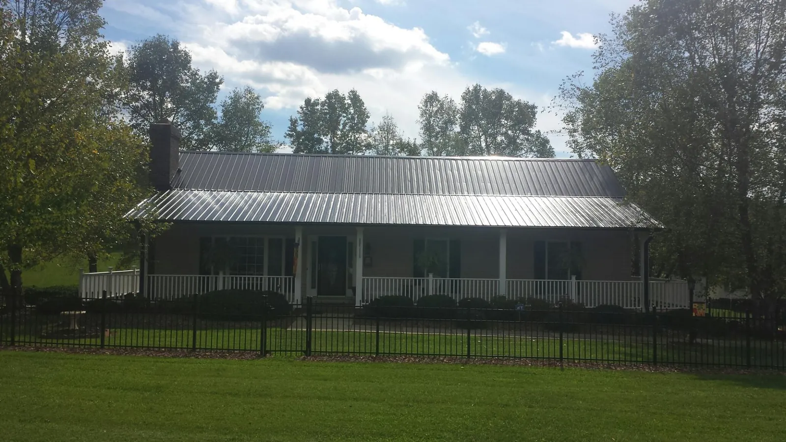 Gray metal roof on a brick ranch with a full width front porch — Gutter Guard Installation work by our crew in Anadarko