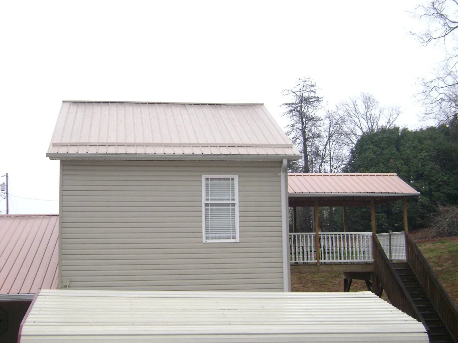 Tan metal roofs on a two story addition and attached porch, from a Roof Replacement job in Anadarko