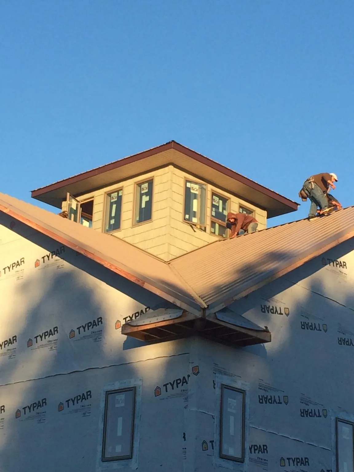Roofers working around a rooftop cupola on a new metal roof at sunset — Roof Waterproofing in Anadarko by Roofing Brothers